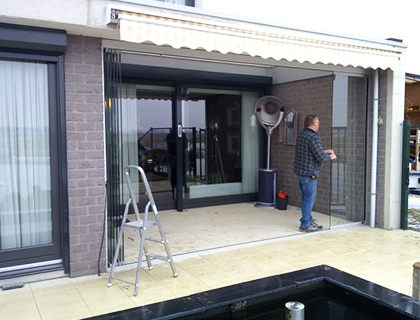 Terrasbeglazing Glazen vouwwand met glaspanelen zonder staande profielen in open toestand.